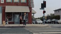 a man walking across a street next to a traffic light