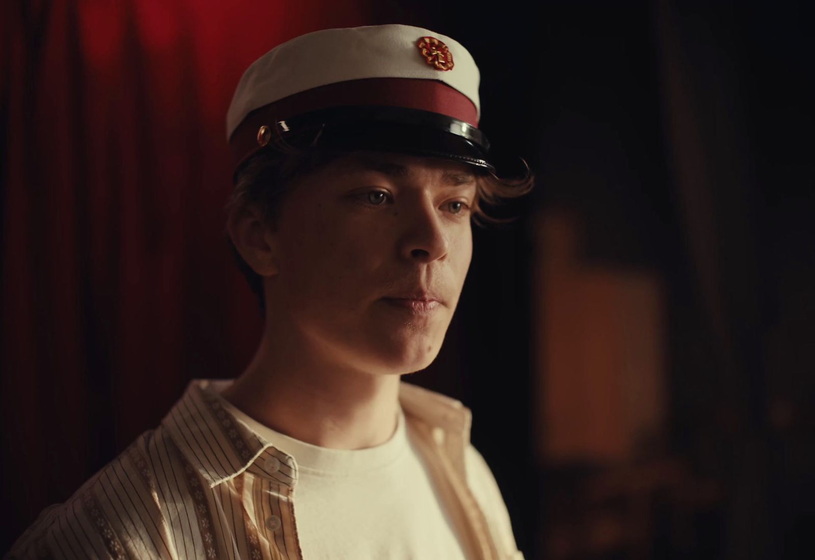 a young man wearing a sailor's hat in a dark room
