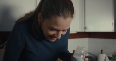 a woman holding a bottle of water in a kitchen