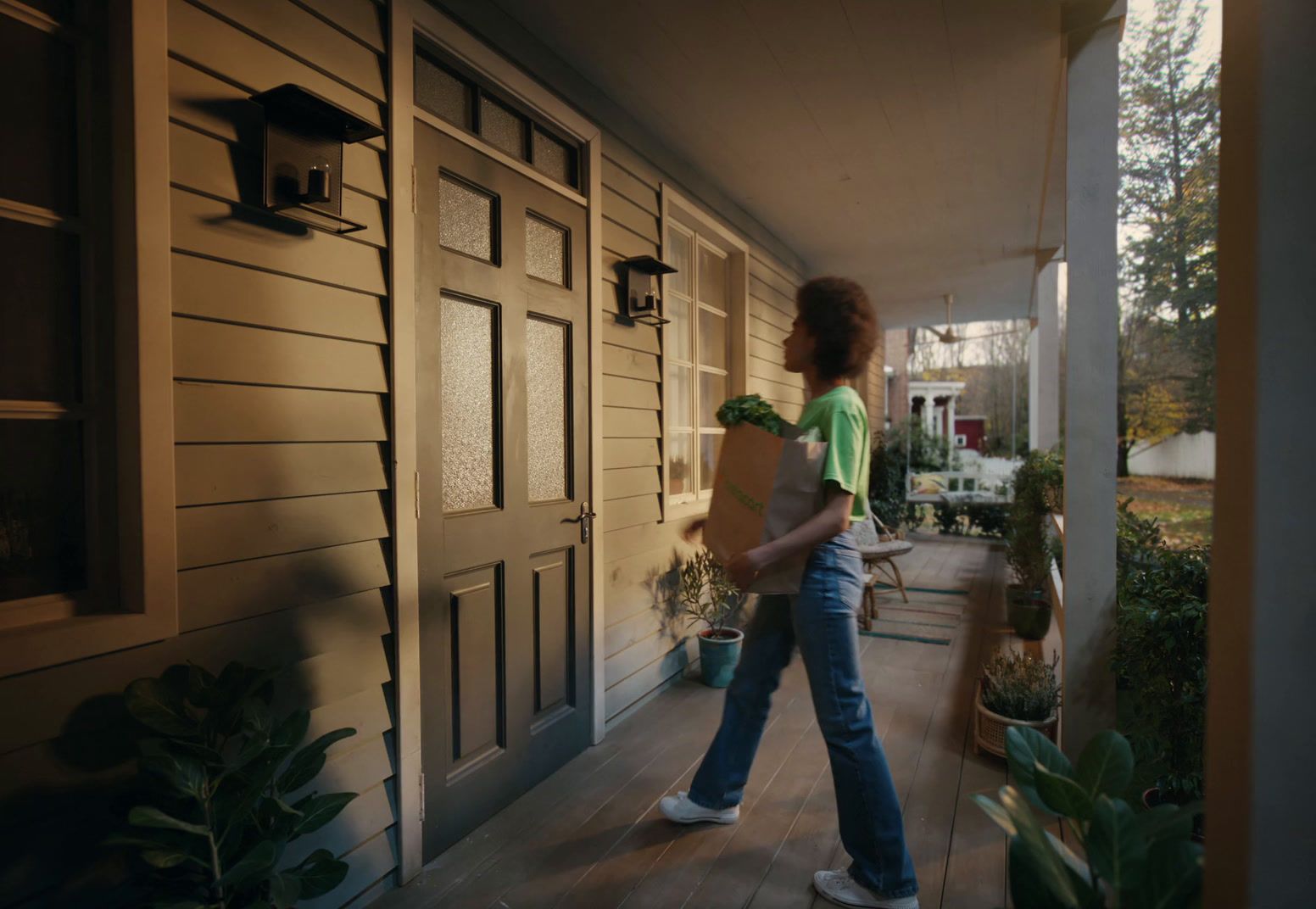 a woman walking down a porch carrying a box