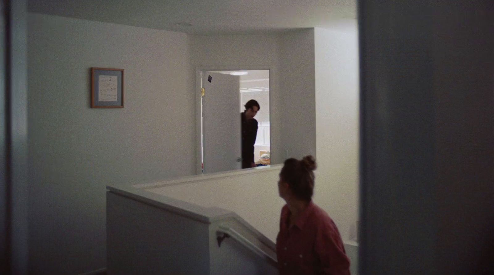 two women standing in a hallway looking at a mirror