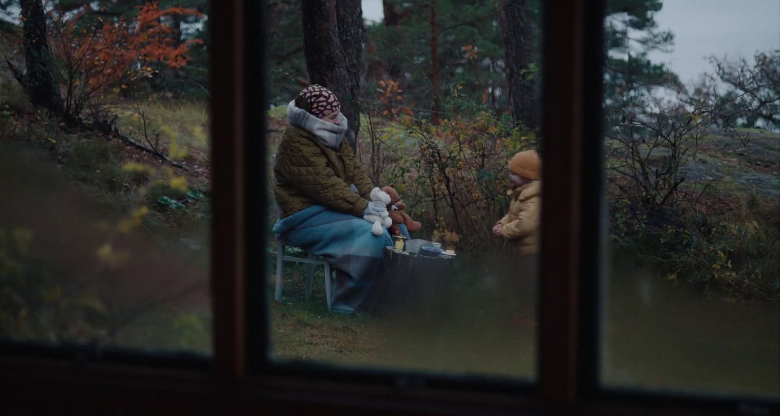 two people sitting on a bench in the woods