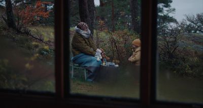 two people sitting on a bench in the woods