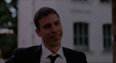 a man in a suit and tie standing in front of a building