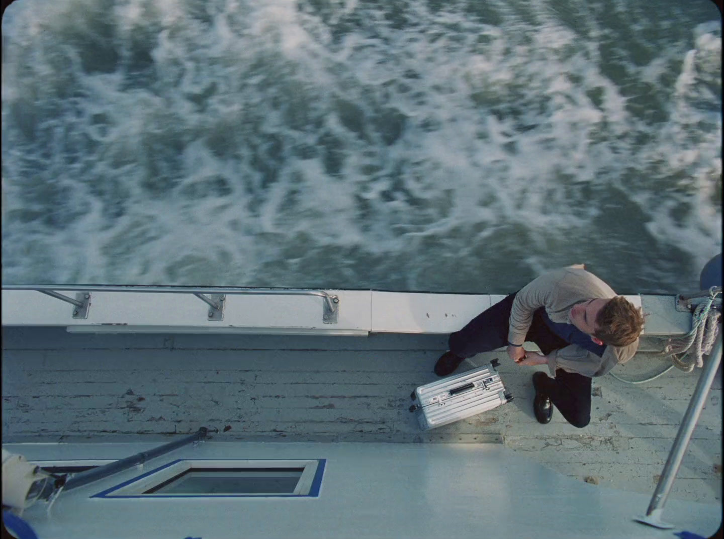 a man sitting on the side of a boat next to the ocean