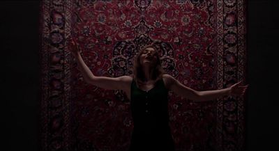 a woman standing in front of a rug with her arms outstretched