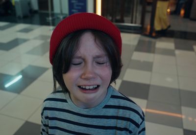 a young boy wearing a red hat while looking at a cell phone