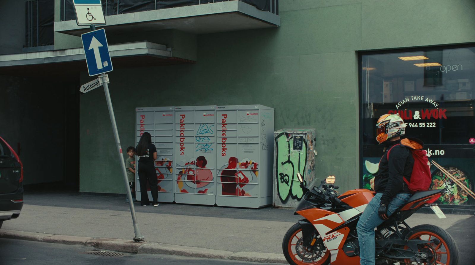 a man riding a motorcycle down a street next to a tall building