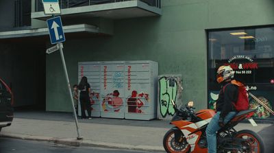 a man riding a motorcycle down a street next to a tall building