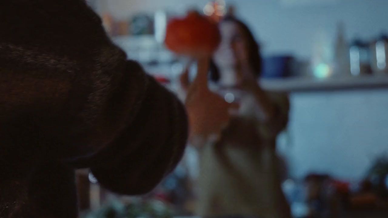 a woman standing in a kitchen holding a red apple