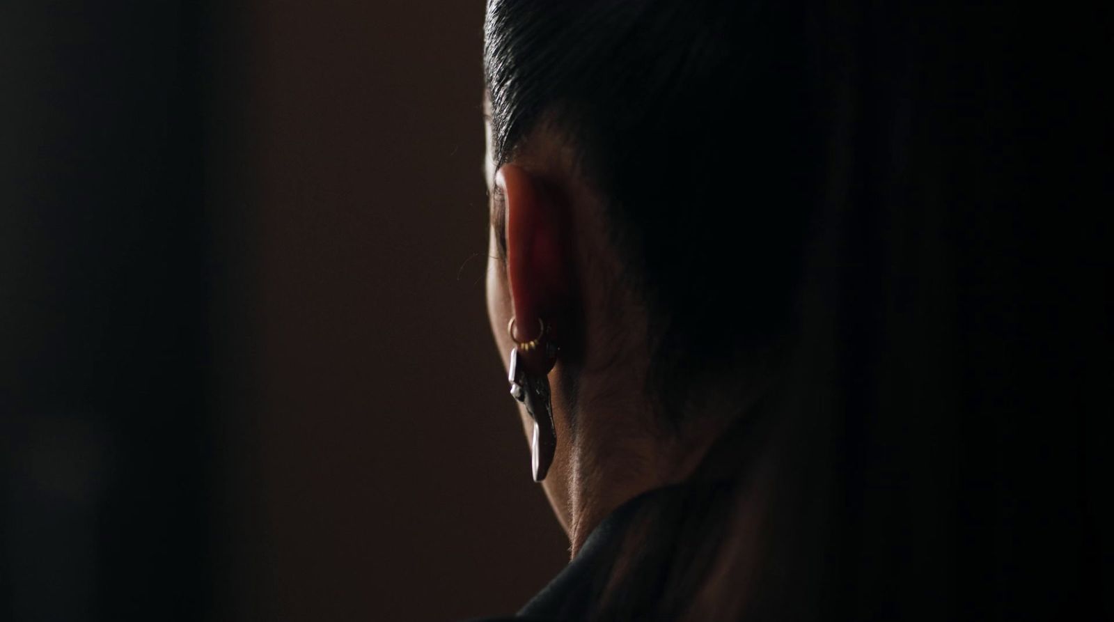 a man in a dark room looking out a window