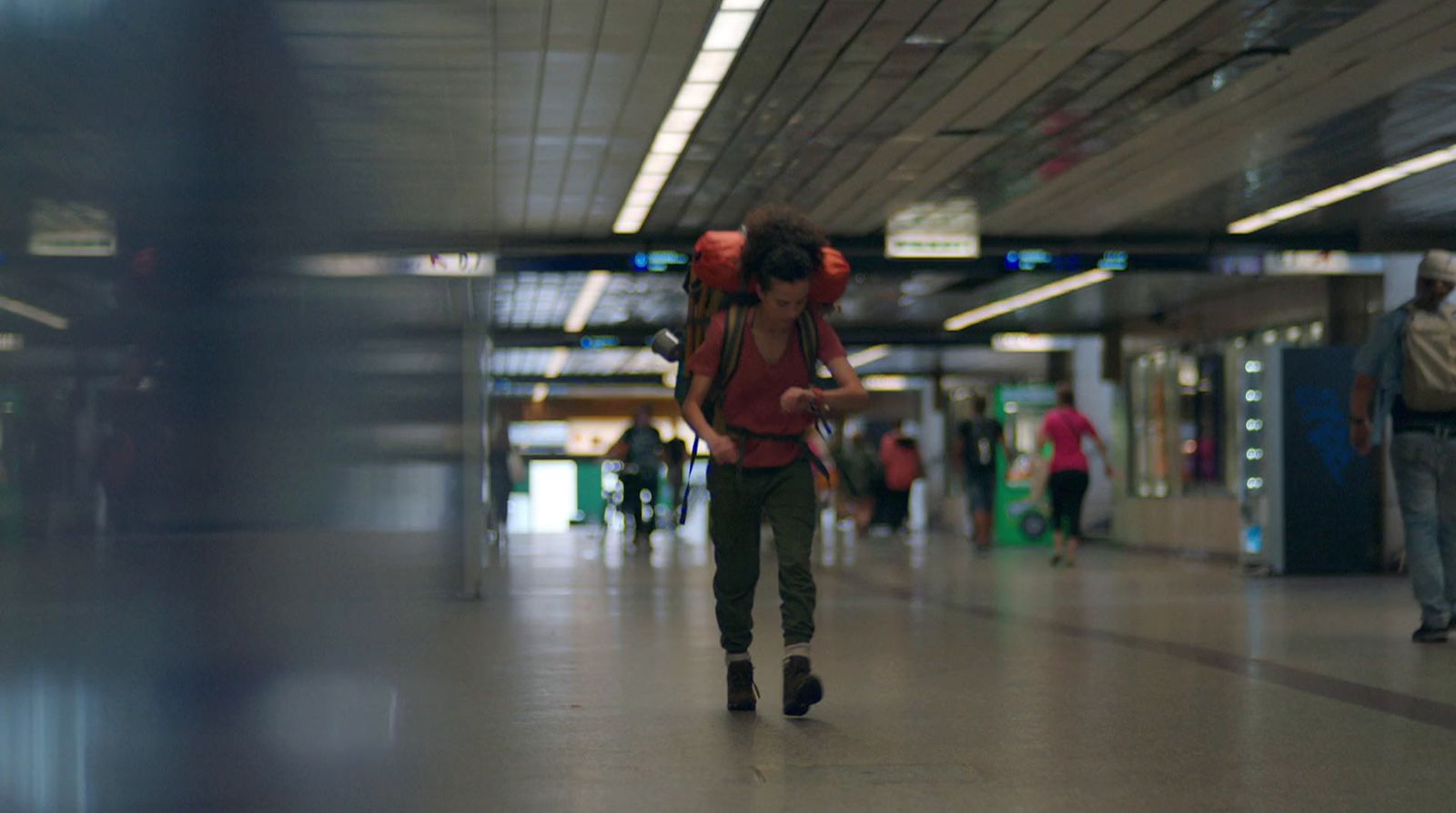 a woman walking through a terminal holding a cell phone