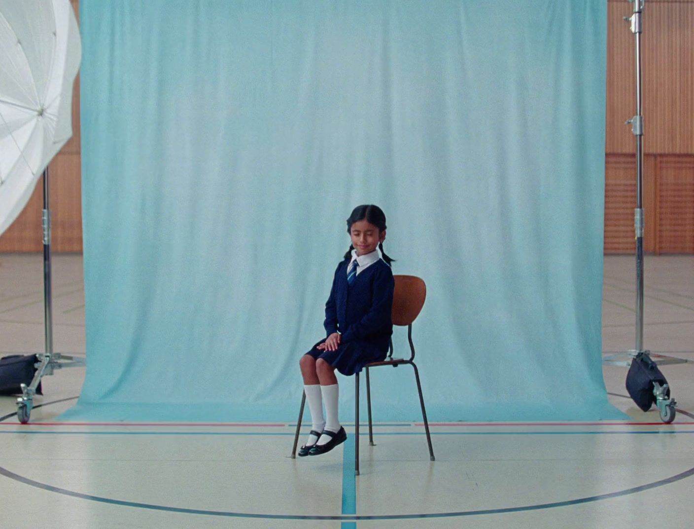 a young girl sitting in a chair in front of a blue backdrop