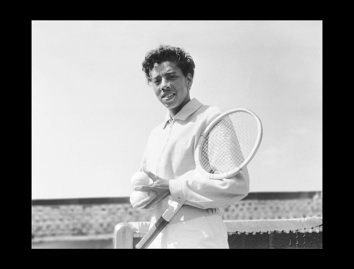 a black and white photo of a man holding a tennis racket