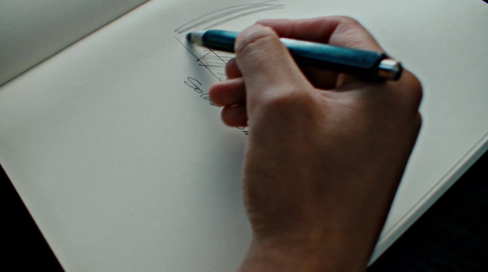 a person writing on a piece of paper with a pen