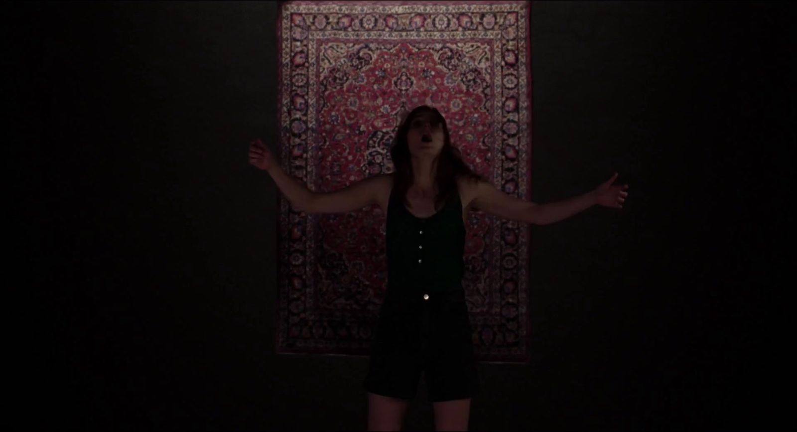 a woman standing in front of a rug in the dark