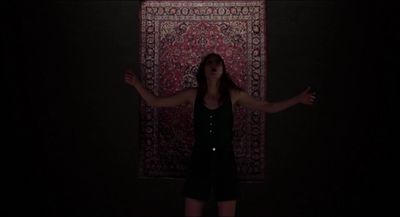 a woman standing in front of a rug in the dark