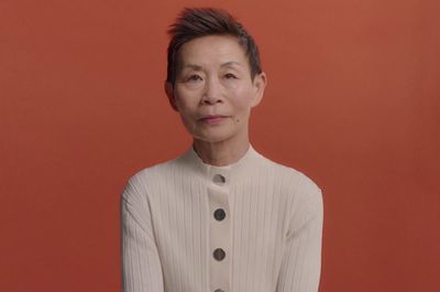 a woman with short hair standing in front of a red wall