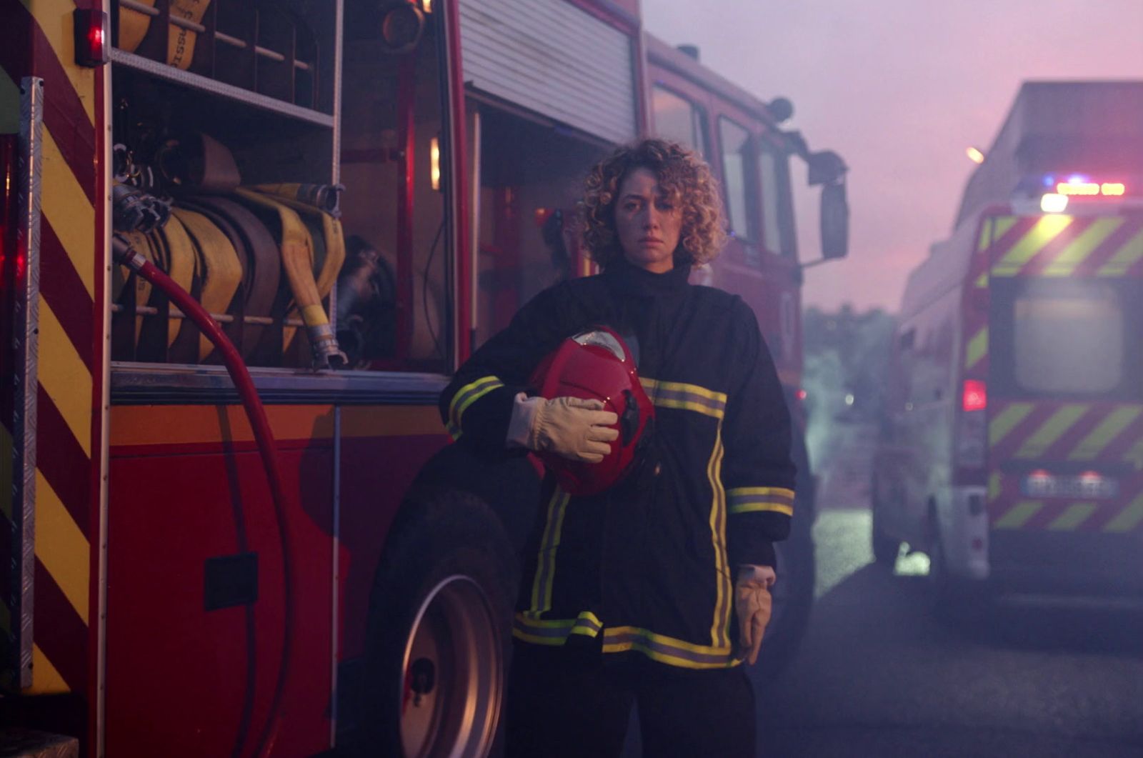 a woman in a firefighter's uniform standing in front of a fire truck