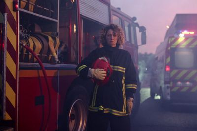 a woman in a firefighter's uniform standing in front of a fire truck