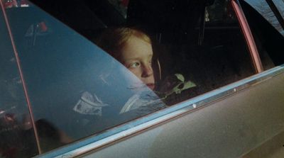 a little girl sitting in a car looking out the window