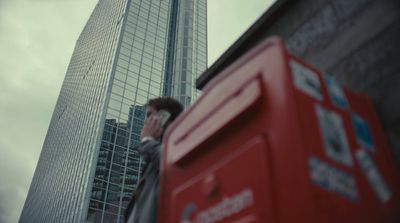a man talking on a cell phone in front of a tall building