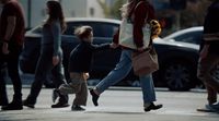 a woman holding a child's hand as they cross the street