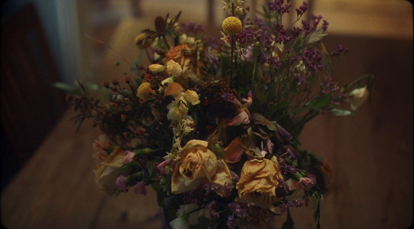 a vase filled with lots of flowers on top of a wooden table