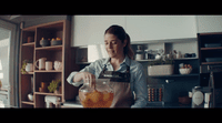 a woman is pouring something into a blender