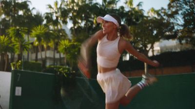 a woman in a white dress playing a game of tennis