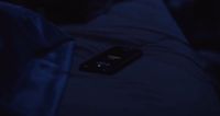 a cell phone sitting on top of a bed in the dark