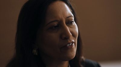 a close up of a person wearing a suit and earrings