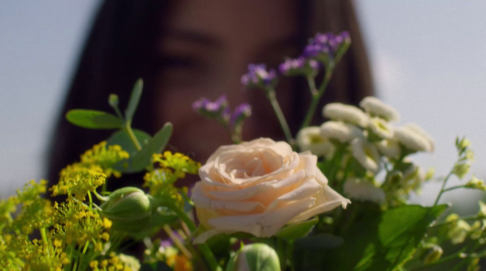 a close up of a bouquet of flowers with a woman in the background