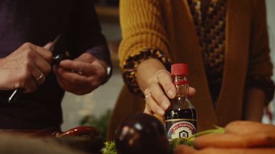 a person is holding a bottle of ketchup next to a pile of carrot