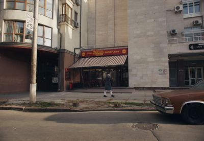 a person walking down the street in front of a building