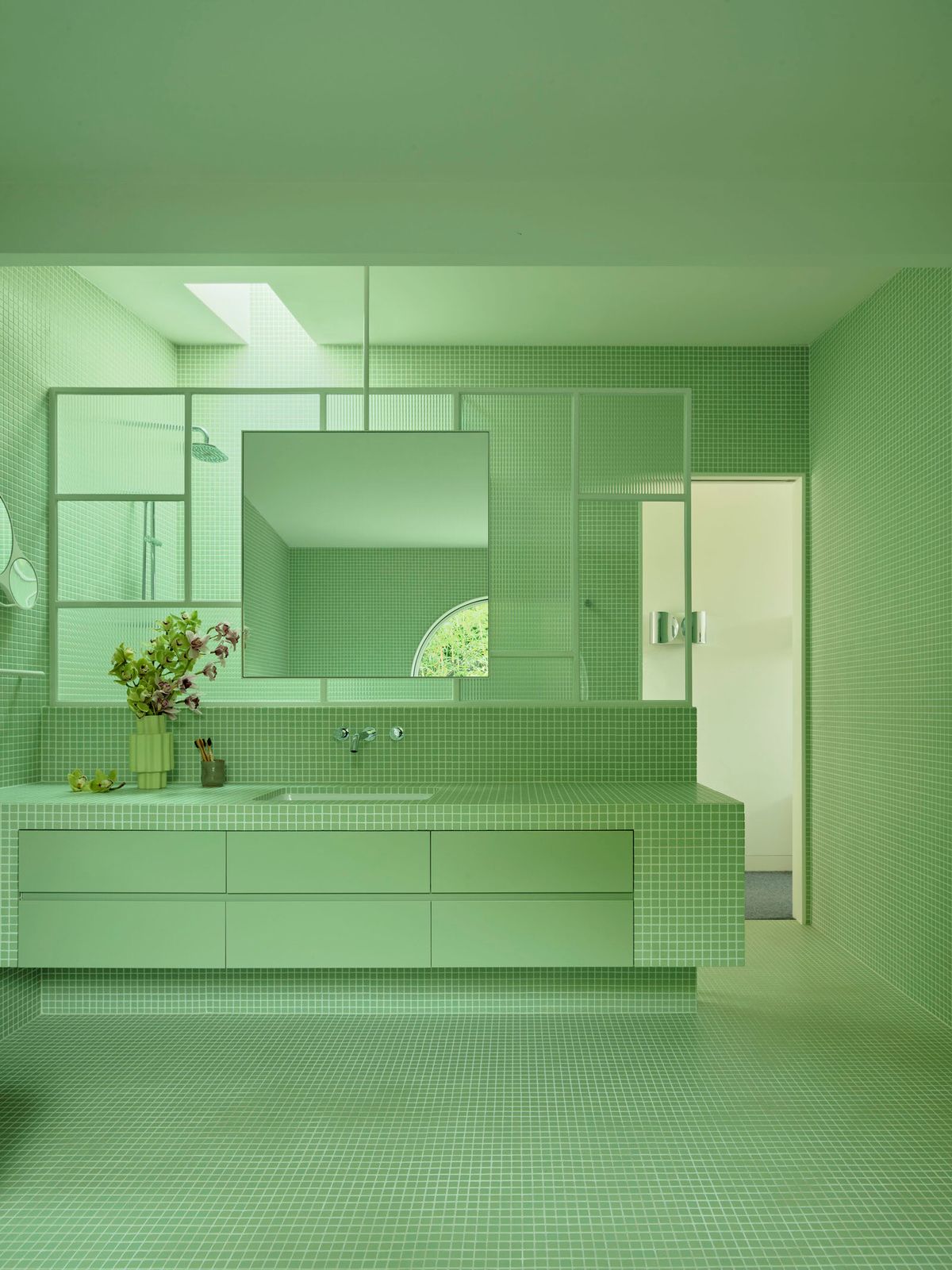 a bathroom with a green tiled floor and walls