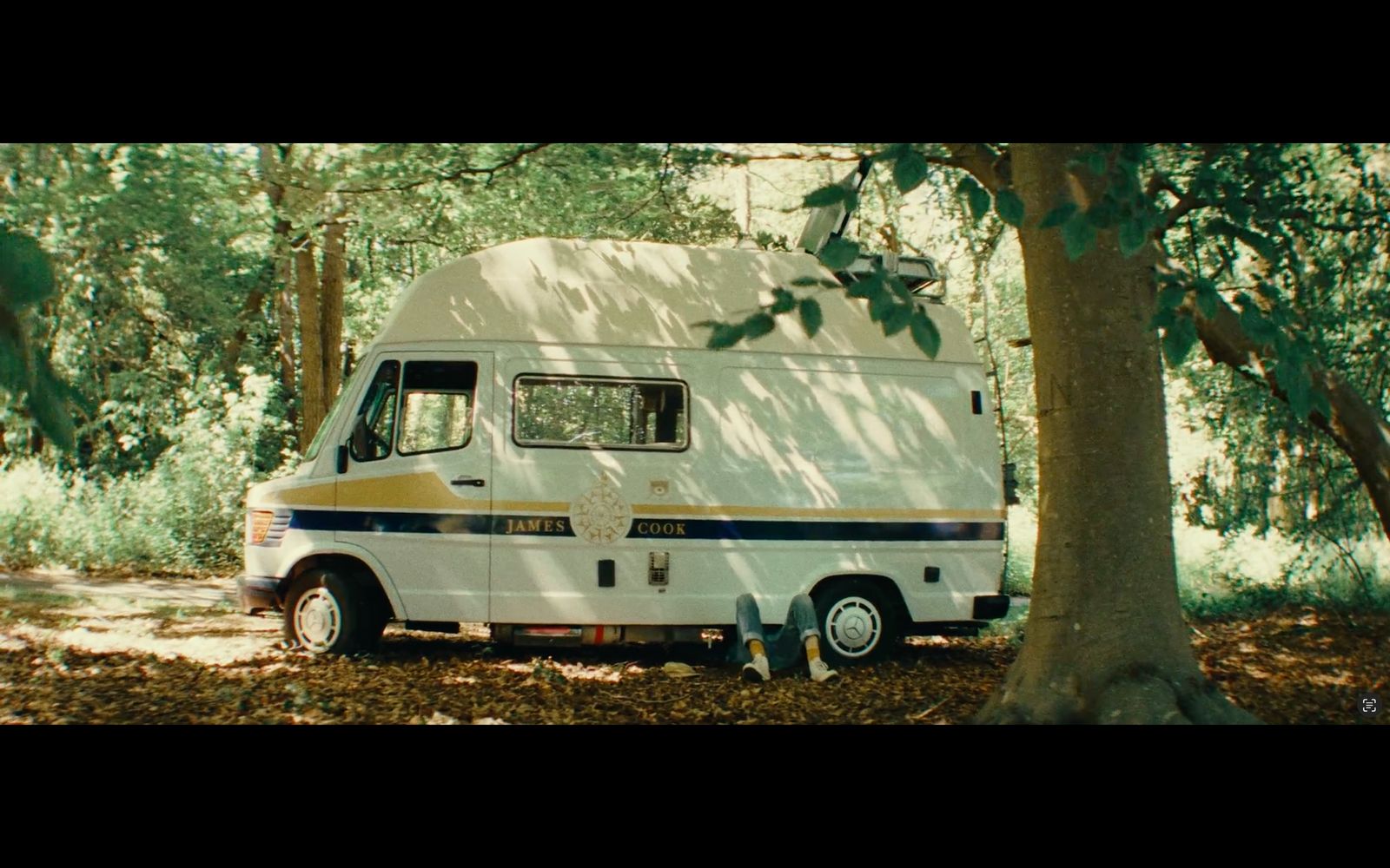 an rv parked in the woods next to a tree