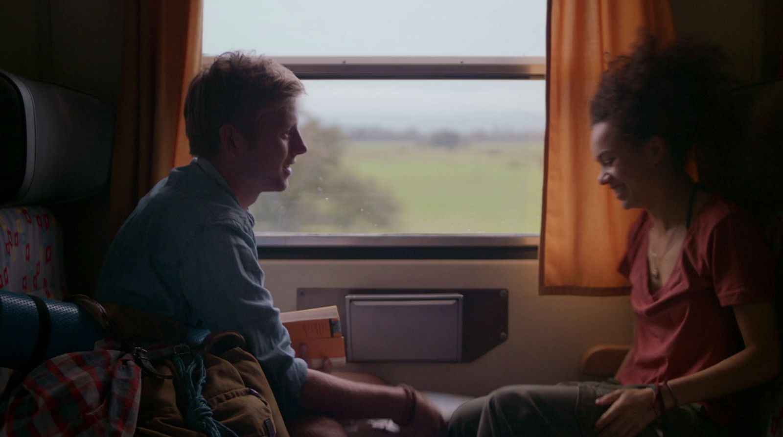 a man and a woman sitting on a train looking out the window