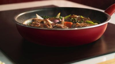 a red pan filled with food on top of a stove