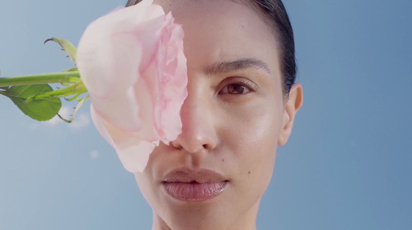 a woman holding a pink flower to her face