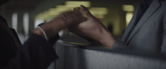 a man in a suit and a woman in a white shirt hold their hands together