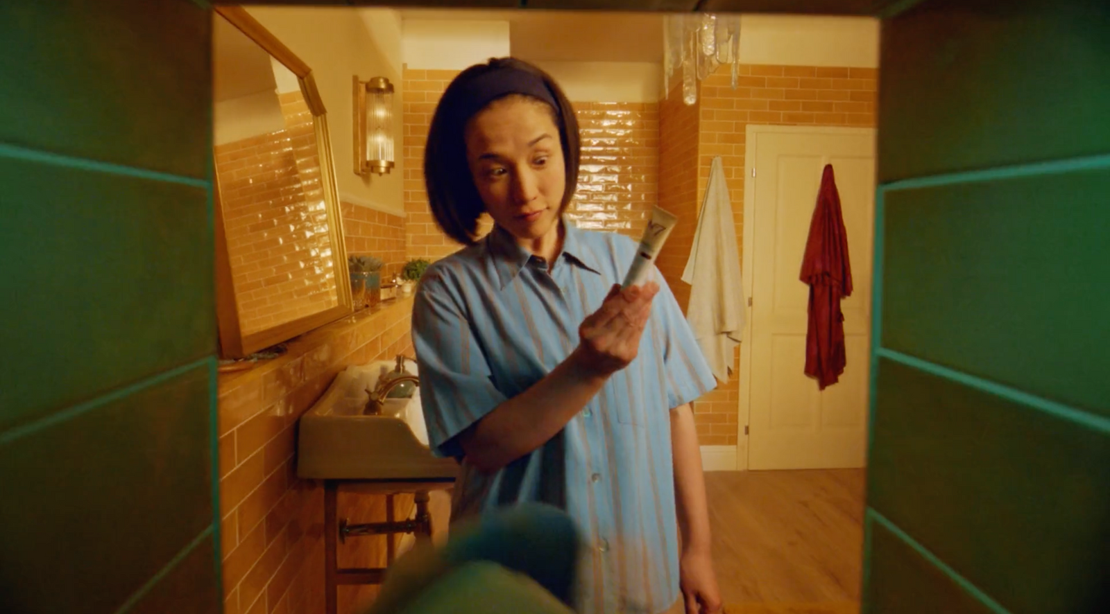 a woman standing in a bathroom holding a knife