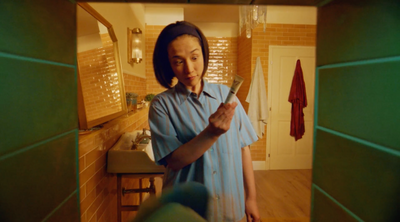 a woman standing in a bathroom holding a knife