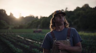 a man standing in a field with a hat on