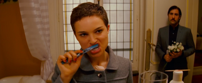 a woman brushing her teeth in front of a man