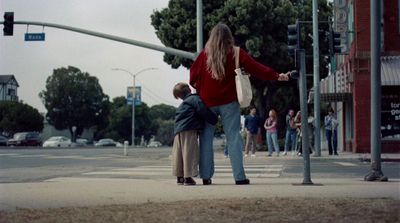 a woman standing next to a little boy on a street