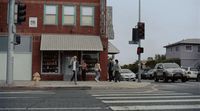 a group of people walking across a street next to a traffic light