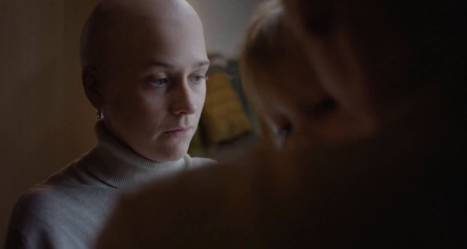 a woman with a bald head looking in a mirror
