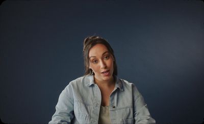 a woman sitting at a table with a blue background