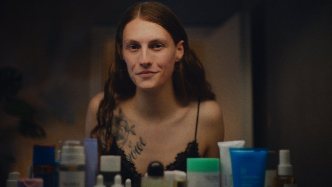 a woman sitting in front of a mirror with lots of skin care products